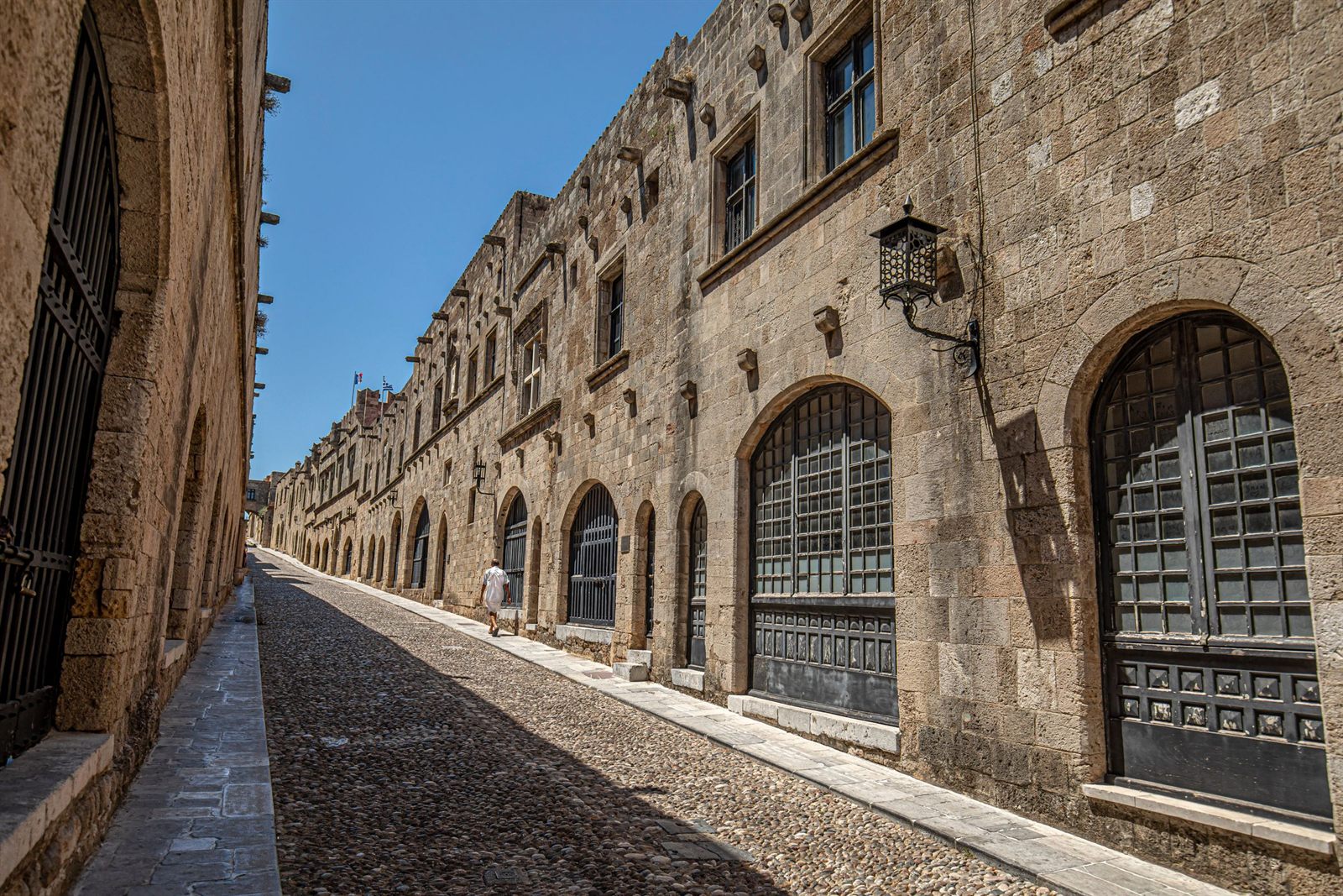 Medieval stone street lined with arched doorways in an old Mediterranean town