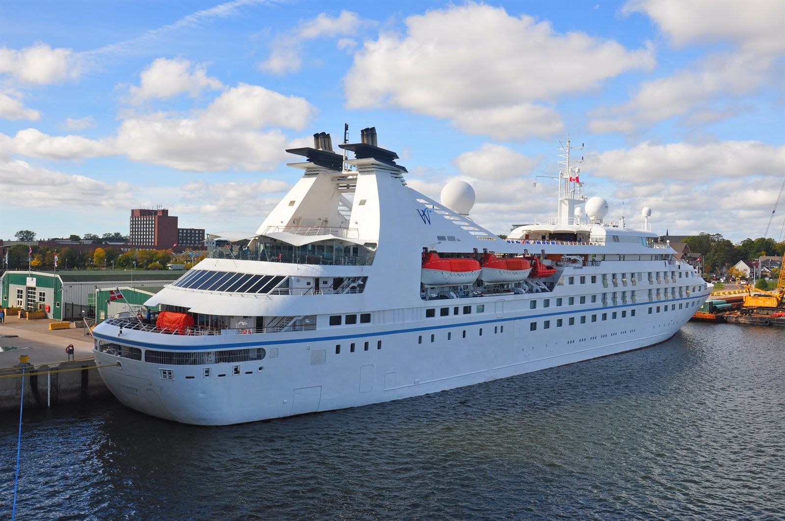Small white cruise ship moored at a quay in a quiet harbor town